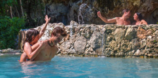 4 people swimming in a waterfall